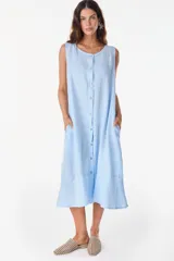Vestido midi celeste de lino italiano, sin mangas, con escote redondo y cierre frontal abotonado con bolsillos laterales y corte holgado.
