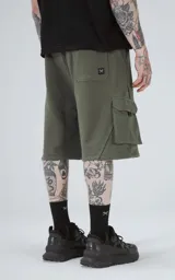 Bermuda de algodón rústico color verde militar, de calce oversize, con cintura elástica y bolsillos cargo con cierre en los laterales.