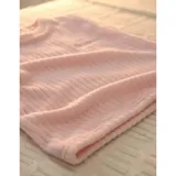 Conjunto de pijama de dos piezas confeccionado en tela de plush texturizada con diseño de rayas verticales en relieve. Incluye una remera de manga larga con cuello redondo y un pantalón de corte holgado. La remera presenta un pequeño bordado decorativo en el pecho.