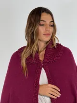 Ruana de lambswool color gris oscuro, con cuello alto y detalles bordados a mano en relieve en el cuello y a lo largo de la abertura frontal.