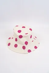 Gorro tipo bucket color crema con estampado de lunares fucsias.