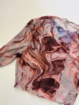 Top de microtul con estampado abstracto en tonos marrones, celestes y blancos, de cuello alto y mangas largas.