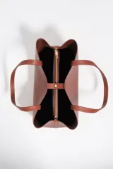 Bolso shopper Bimba Y Lola color marrón, de tamaño grande con exterior de piel vacuna. Presenta doble asa de hombro, cierre con botón de presión y logo grabado en letras doradas en la parte frontal.