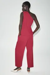 Pantalón de tiro bajo color fucsia, con pliegues delanteros, bolsillos frontales, pernera holgada y cierre frontal con cremallera y botón.