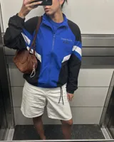 Campera deportiva de diseño colorblock en tonos azul, negro y blanco, con cierre frontal y cuello alto. Presenta detalles de franjas y un pequeño estampado en el pecho con la inscripción "Uruguay Run Club".