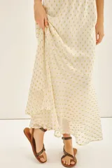 Falda larga de tiro alto, calce amplio, color crema con puntos dorados brillantes (lurex). La cintura es elástica en la parte trasera y tiene frunces.