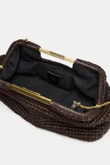 Bolso tipo sobre color marrón, con cuerpo trenzado y asa de mano rígida dorada. Incluye correa bandolera de cadena extraíble y cierre magnético.