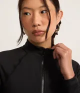 Blusa negra de microfibra con cuello alto y cierre frontal con cremallera, de manga larga y corte ajustado.