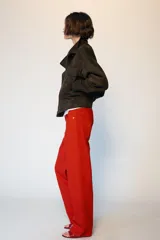 Cazadora tipo bomber de tejido efecto ante color marrón oscuro, con cuello subido, manga larga y cierre frontal con cremallera y botones ocultos. Presenta bolsillos frontales con solapa y botones metálicos.