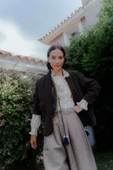 Camisa de corte clásico con patrón de rayas verticales, cuello con volados y mangas largas con puños también decorados con volados.