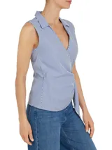 Blusa sin mangas con cuello camisero, diseño cruzado con lazo en la cintura y estampado a rayas verticales azules y blancas.