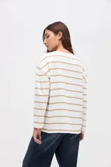 Remera de manga larga con diseño a rayas horizontales en color crema y rojo. Presenta un corte holgado, cuello redondo y un pequeño bordado en el pecho.