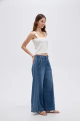 Pantalón jean azul de tiro alto, corte baggy y piernas anchas, con costuras decorativas frontales.