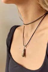 Gargantilla de cuero negro con dije de piedra blanca en forma de lágrima con engarce dorado.