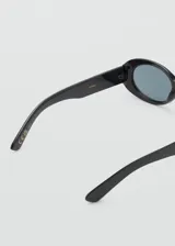 Gafas de sol con diseño ovalado y montura de pasta color negro, con cristales oscuros.