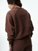 Campera deportiva color bordó con cuello tipo bomber, cierre frontal completo y mangas raglán. Presenta puños, cuello y ruedo acanalados, además de bolsillos frontales.