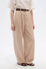 Pantalón de lyocell color beige, de tiro alto, corte ancho y diseño plisado con bolsillos laterales.