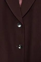 Abrigo de paño color beige con cuello solapa, manga larga con hombreras y cierre frontal con botones. Presenta bolsillos delanteros de doble vivo y abertura en la espalda.