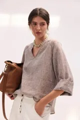 Blusa de lino color beige, de calce relajado, mangas amplias tres cuartos, escote en V y ruedo curvo.