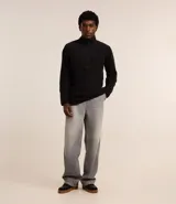 Saco de polar negro con cuello alto y cierre frontal parcial, de manga larga y diseño de corte recto.