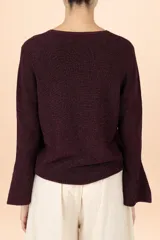 Suéter de punto color púrpura con cuello perkins, manga larga y puños acampanados. Presenta una textura sutil con acabado brillante.