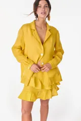 Blazer de lino italiano color amarillo mostaza, de botonadura sencilla con dos botones, solapas clásicas y mangas largas con puños tableados.
