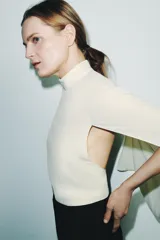 Camisa de viscosa con cuello subido y diseño de manga tipo capa con aberturas laterales. Presenta un corte fluido y cierre posterior con cremallera oculta.