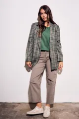 Blazer de corte recto con estampado de cuadros en tonos verdes y grises. Presenta solapas clásicas, cierre frontal y bolsillos laterales.