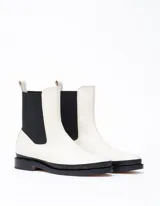 Bota Chelsea color hueso de cuero vacuno, con elástico lateral negro y suela de cuero.