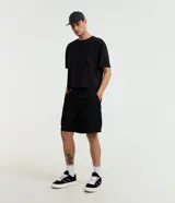 Bermuda cargo baggy negra, confeccionada en poliéster con cintura elástica, cordón ajustable y bolsillos laterales con cierre de cremallera.