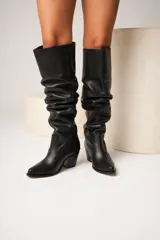 Botas de cuero negro con caña alta arrugada y taco cuadrado.