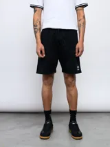 Bermuda básica de felpa negra con cordón ajustable en la cintura y el logo de la marca bordado en blanco en la pierna izquierda.
