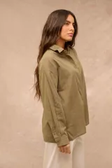Camisa verde oliva de manga larga, corte oversize, con cuello camisero, cierre frontal de botones y un bolsillo aplicado en el pecho.
