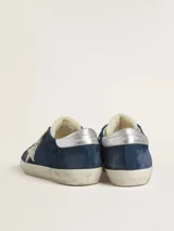 Zapatillas urbanas Golden Goose modelo Super-Star, color azul con efecto desgastado, estrella blanca en el lateral, talón plateado y cordones blancos.