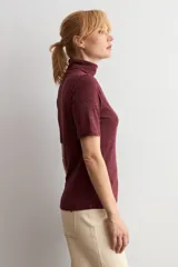 Polera de manga corta con cuello alto, confeccionada en tejido acanalado de color bordó con efecto melange.