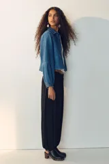 Camisa de denim de mezcla de algodón y lyocell, de corte corto, con cuello clásico, mangas largas abullonadas y cierre frontal con botones oscuros.