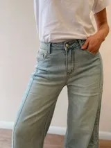 Pantalón jeans tipo palazzo de corte amplio y tiro medio-alto, con lavado celeste vintage y dobladillo vuelto con detalle de rayas en la terminación. Cuenta con bolsillos delanteros y traseros.