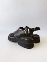 Sandalias negras de cuero con tiras cruzadas, plataforma track y hebilla lateral.