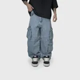 Pantalón cargo de jean con corte ultra baggy, diseño de pierna ancha y múltiples bolsillos laterales con solapa. Confeccionado en denim de algodón con textura rústica.
