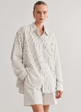 Camisa de corte oversize, con diseño a rayas verticales, cuello camisero, cierre frontal con botones y un bolsillo aplicado en el pecho.