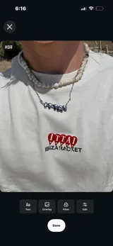 Remera color crema de corte oversize con estampado en la espalda que incluye cuatro paletas de pádel rojas con la palabra 'ITTAI' perforada, y texto debajo que dice 'IBIZA RACKET ITTAI STARS'.