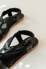 Sandalias chatitas de cuero en tono nude, con diseño de tiras cruzadas en el empeine y elástico en el talón para mayor ajuste. Presentan una plantilla acolchada y detalles en cuero charolado en la parte posterior.