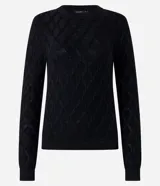 Blusa de manga larga negra confeccionada en punto de viscosa con poliamida e hilos metálicos, con cuello redondo y hombreras. Presenta textura de rayas curvas que forman rombos.