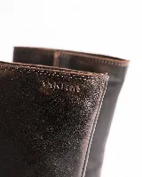 Bota de cuero negra con caña media, punta cuadrada, taco bloque y arnés con hebillas y tachas plateadas.