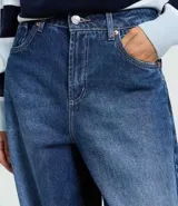 Pantalón de jean azul con corte barrel, cintura alta y estructura amplia. Presenta diseño de cinco bolsillos, cierre frontal con botón y trabillas para cinturón.