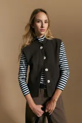 Chaleco de paño color marrón oscuro, de silueta recta y diseño minimalista. Presenta cuello a la base, cierre frontal con botones claros y bolsillos aplicados.