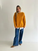 Sweater de punto con textura tipo waffle, color mostaza, de corte holgado, cuello redondo y mangas largas con puños acanalados.