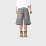 Bermuda baggy de denim color gris con efecto acid wash, corte ancho y largo por debajo de las rodillas. Cuenta con bolsillos traseros grandes con bordes deshilachados y detalle de bordado en el bolsillo derecho.