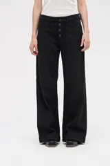 Jean de corte wide leg en color negro, con tiro medio y cierre frontal con botones a la vista. Presenta un diseño holgado desde la cadera hasta el bajo, con pierna ancha.