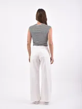 Pantalón de jean blanco roto (off white) de tiro alto y corte ancho (wide leg). Presenta bolsillos cargo grandes con tapa y botón metálico en la parte delantera de los muslos.